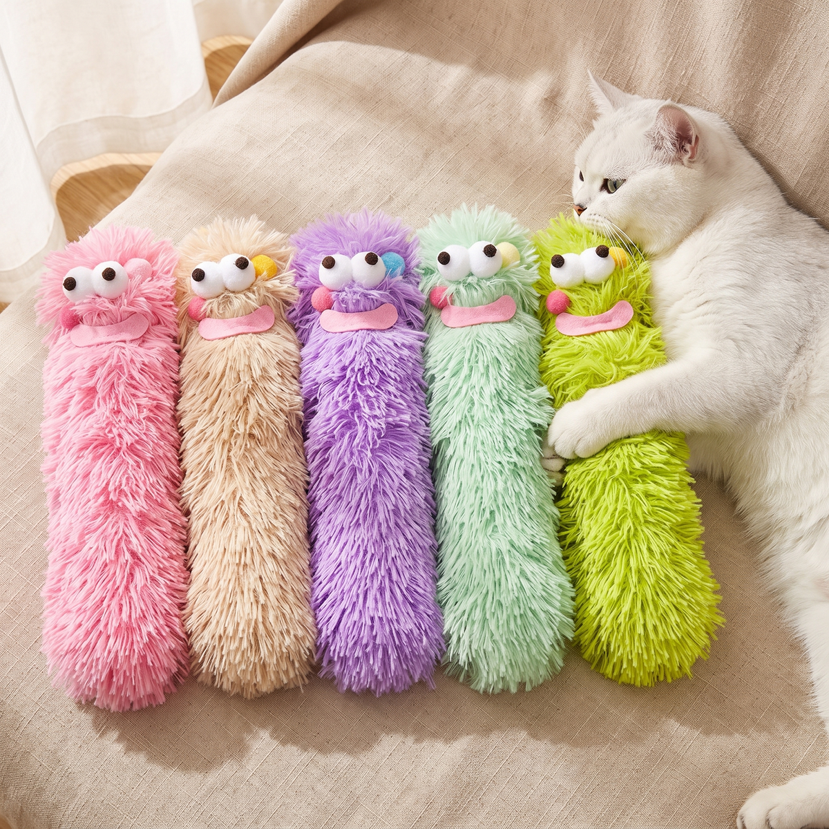 Five fuzzy monster catnip kicker toys with a white cat